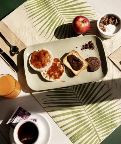 Colazione invitante con pane, marmellata, cioccolato, biscotti, yogurt, succo e tè.