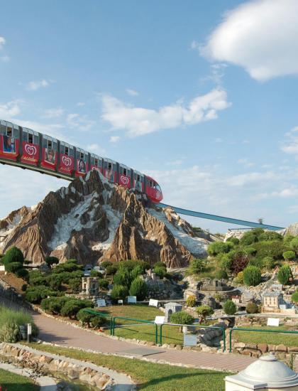 Model train above a miniature landscape with mountains.