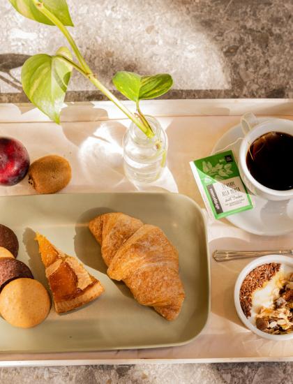 Colazione con croissant, biscotti, frutta, tè e yogurt con cereali.