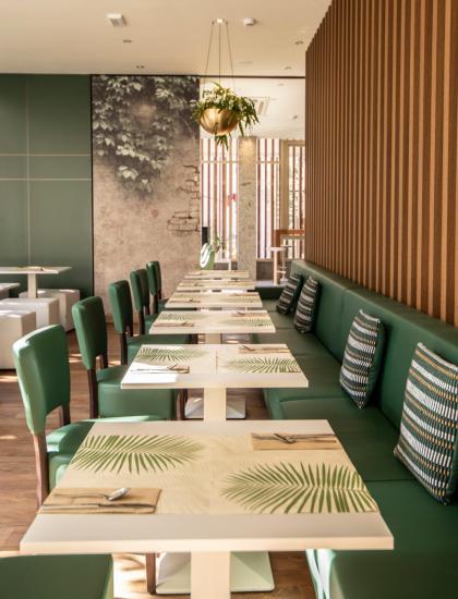 Ristorante moderno con arredi verdi e decorazioni naturali.