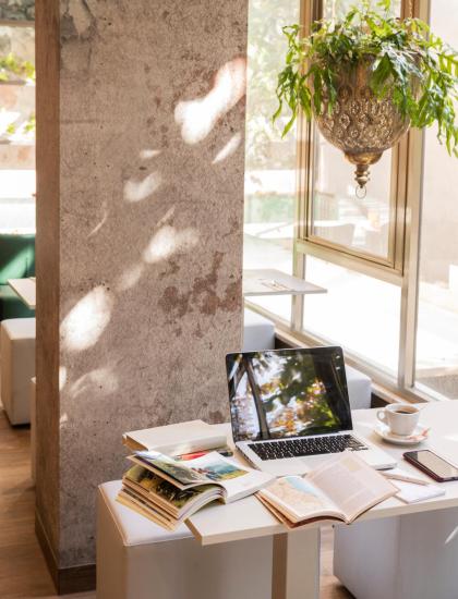 Un angolo di studio con laptop, libri e tazza di caffè vicino alla finestra.
