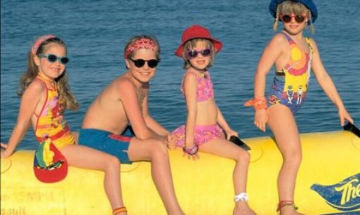 Bambini in costume da bagno seduti su un gonfiabile giallo al mare.