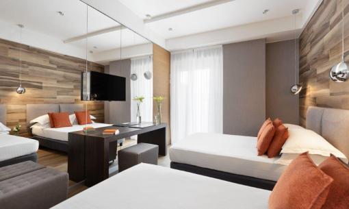 Modern room with beds, orange pillows, and TV.