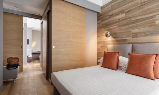 Camera da letto moderna con pareti in legno e cuscini arancioni.