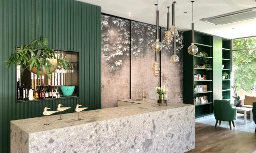Intérieur moderne avec comptoir en granit, étagères vertes et lampes suspendues.