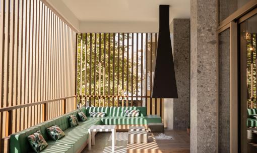Elegante terrazza con divani verdi, camino e pareti in legno.