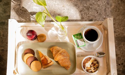 Colazione con croissant, biscotti, frutta, tè e yogurt con cereali.