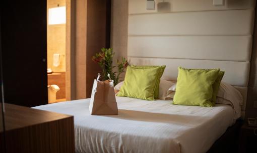 Modern bedroom with green pillows and a paper bag on the bed.