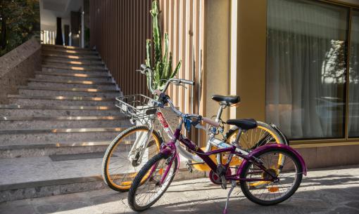 Due biciclette parcheggiate vicino a una scala e una finestra con tende.