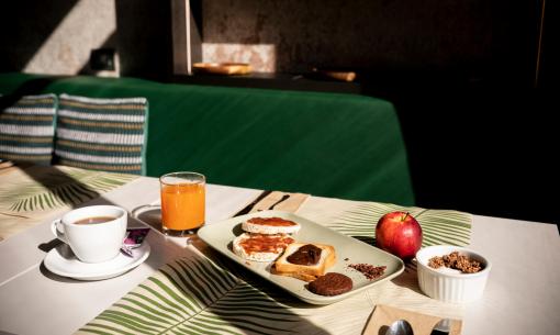 Colazione con tè, succo, pane tostato, mela e yogurt con cereali.