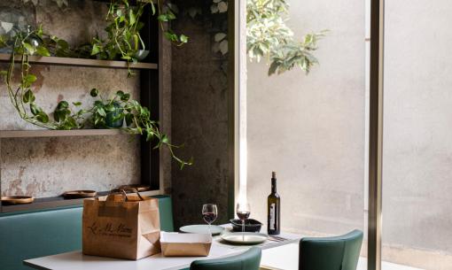 Tavolo da pranzo accogliente con piante e vino, vicino a una grande finestra.