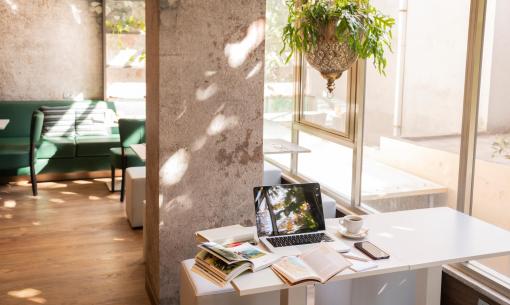 Un angolo di studio con laptop, libri e tazza di caffè vicino alla finestra.