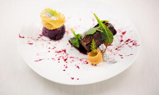 Gourmet dish with meat, vegetables, and artistic decorations.