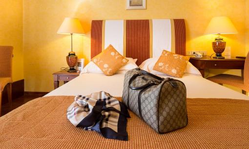 Camera accogliente con letto elegante, lampade calde e borsa di lusso.